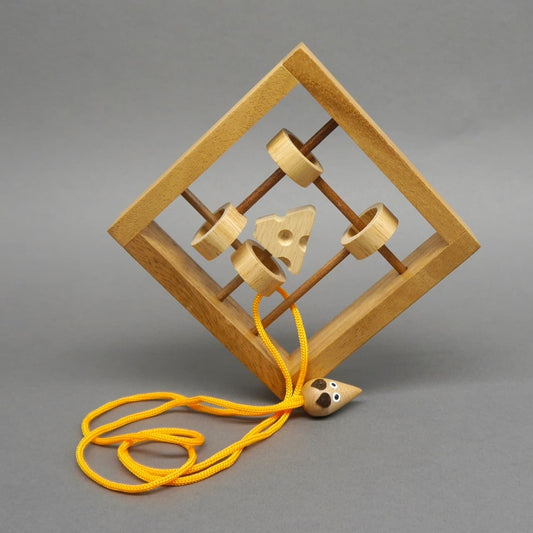 Schräg stehendes Holz-Schnurpuzzle in Mausefalle-Optik; Ringe, Käse und gelbe Schnur mit kleiner Mausfigur bilden das Rätsel.