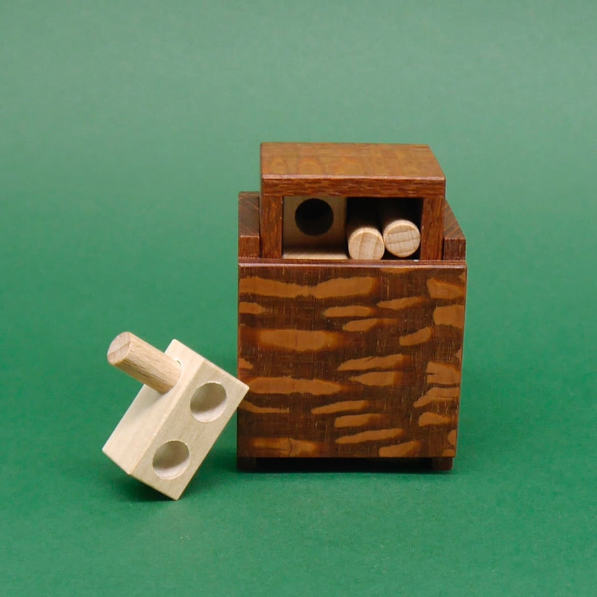 Minima 1st Drawer mit herausragendem 3D-Puzzle-Element vor einer grünen Fläche.