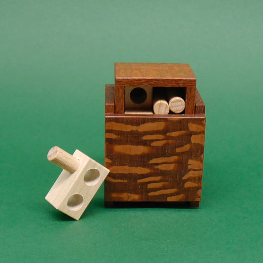 Minima 1st Drawer mit herausragendem 3D-Puzzle-Element vor einer grünen Fläche.