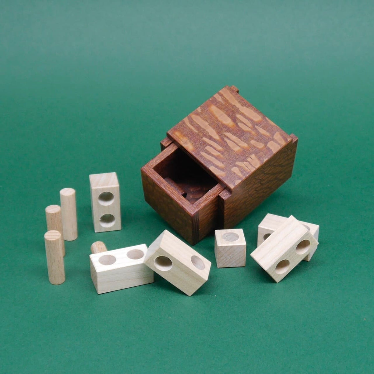 Geöffnetes Holzpuzzle „Minima 1st Drawer“ als Denkspiel, umgeben von mehreren Holzteilen.