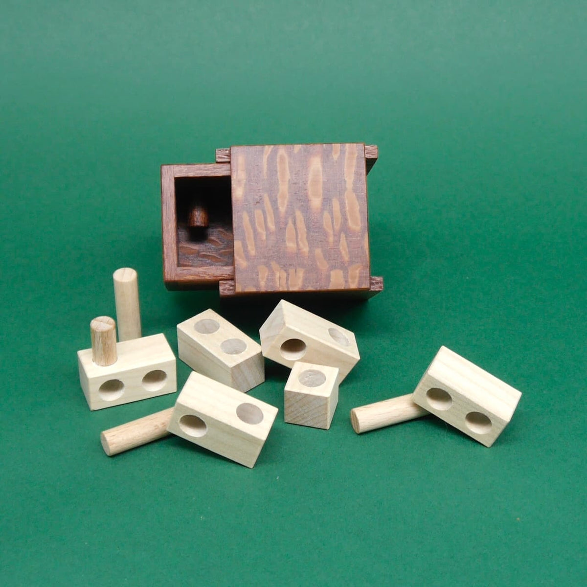 Knobelspiel „Minima 1st Drawer“ mit herausgenommenen Holzblöcken und Zylindern.