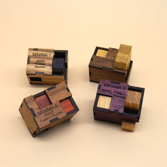 Vier kleine MINIMA‑Holzpuzzles aus verschiedenfarbigen Hölzern bilden ein kompaktes Denkspiele‑Set auf hellem Untergrund.