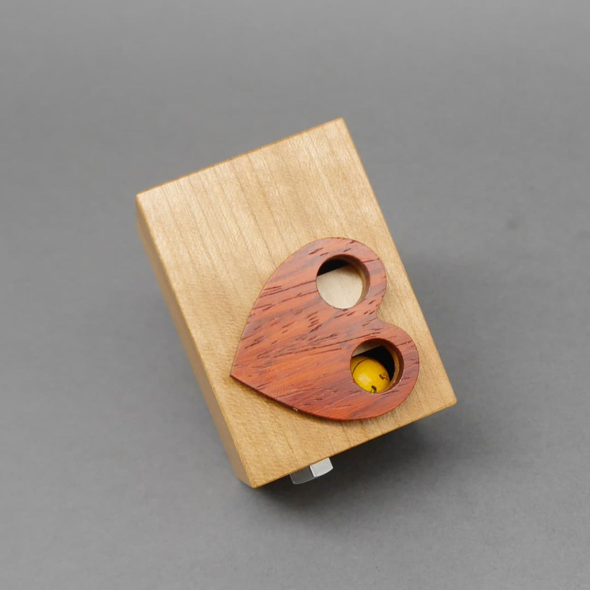 Holzpuzzle in Würfelform mit Herzdetail aus rotem Holz, ein kniffliges Brainpuzzle zum Knobeln.