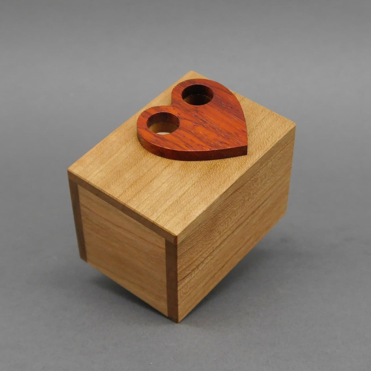 Quadratische Knobelbox aus Holz mit rotem Herzsymbol, ideales Denkspiel zum Knobeln.