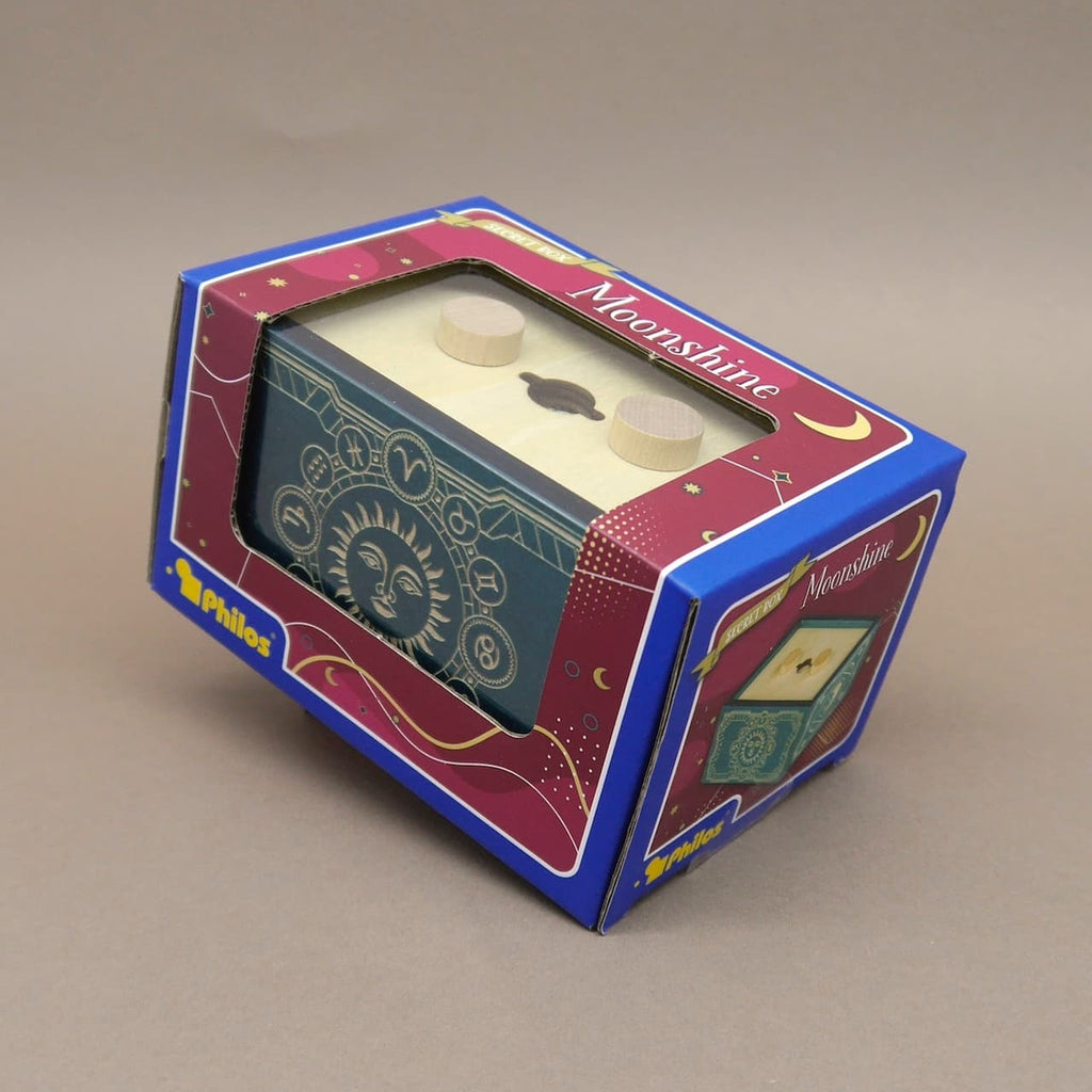 Die „Moonshine“-Puzzlebox in einer blau-pinkfarbenen Geschenkverpackung mit Sichtfenster; das verziert-astrologische Kästchen ist gut durch die Kartonöffnung zu erkennen.