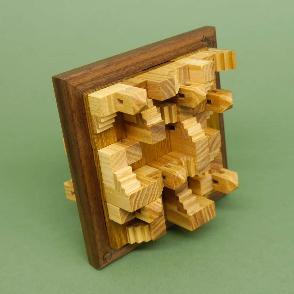 Zusammengebautes Holzpuzzle mit detailreichen, stufenartigen Strukturen, die aus einem quadratischen Holzrahmen herausragen.