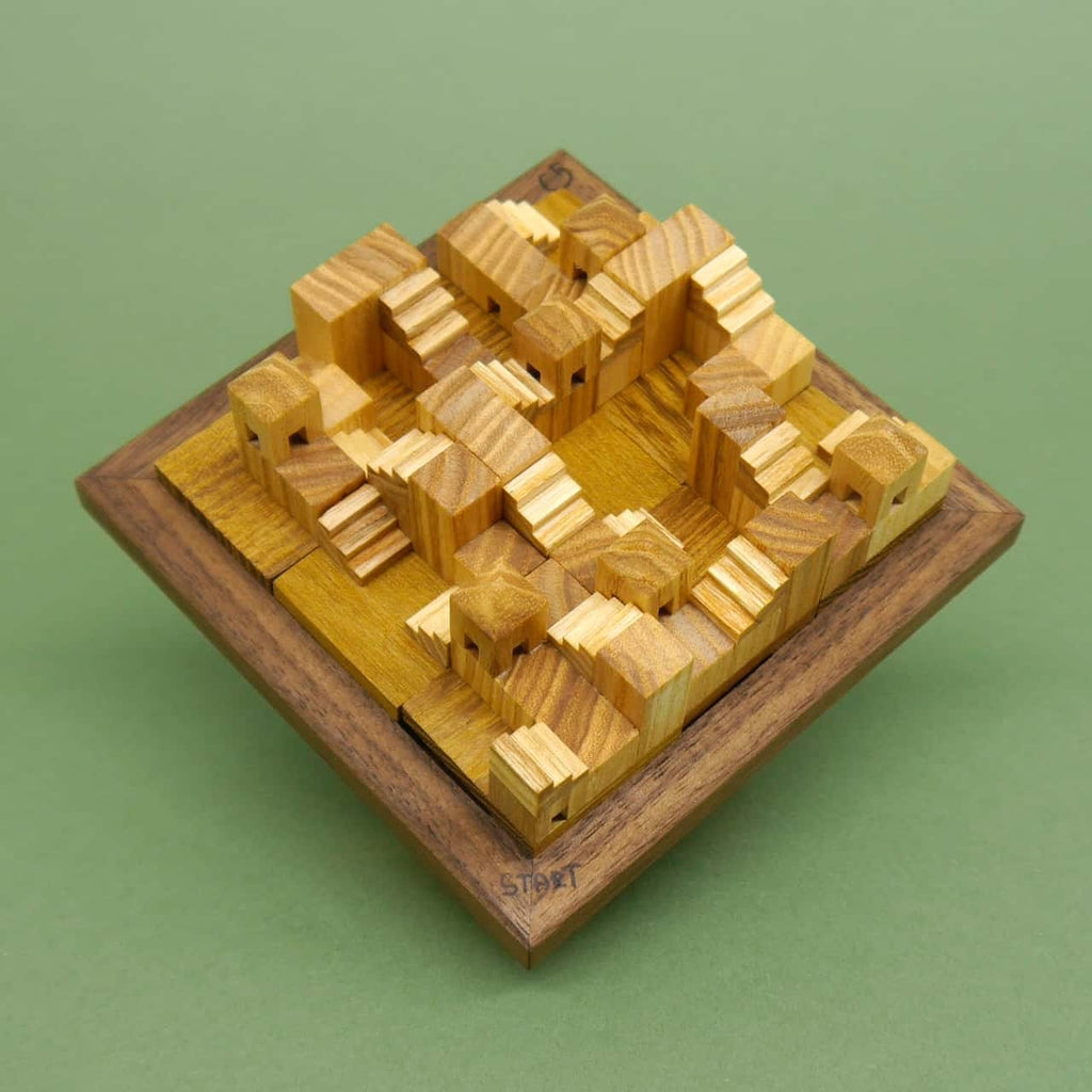 Komplett zusammengesetztes Holzpuzzle mit stufenförmigen Bauteilen in einem quadratischen Rahmen, das wie eine Miniaturlandschaft wirkt.