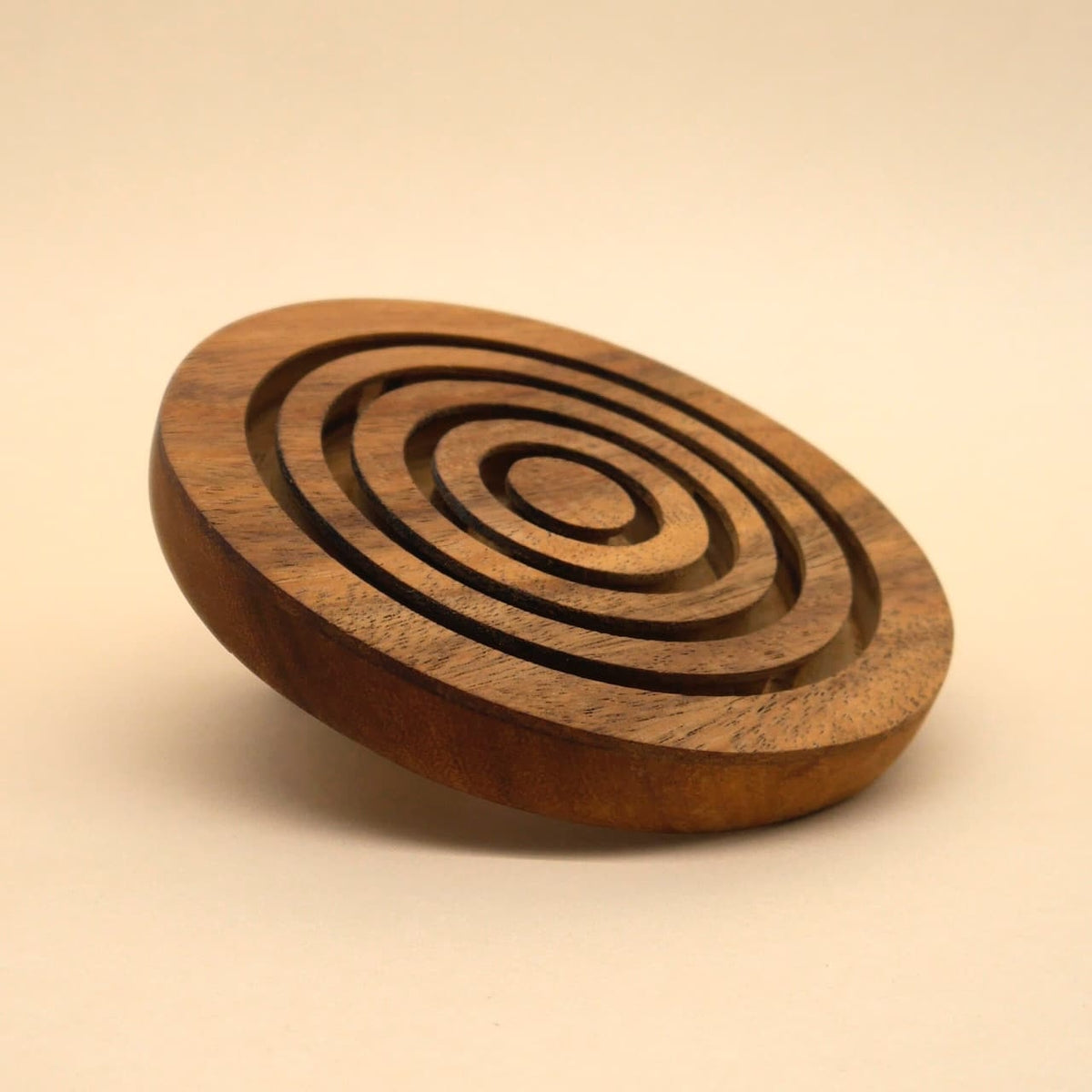 Schräg aufliegendes Holz‑Kinderspiel in Form eines runden Labyrinths aus konzentrischen Ringen, derzeit ohne sichtbare Kugeln.
