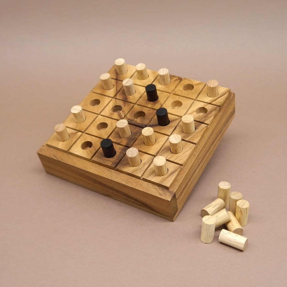 Quadratisches Holz-Taktikspiel mit eingesteckten hellen und dunklen Zylindern; einige Spielsteine liegen seitlich bereit.