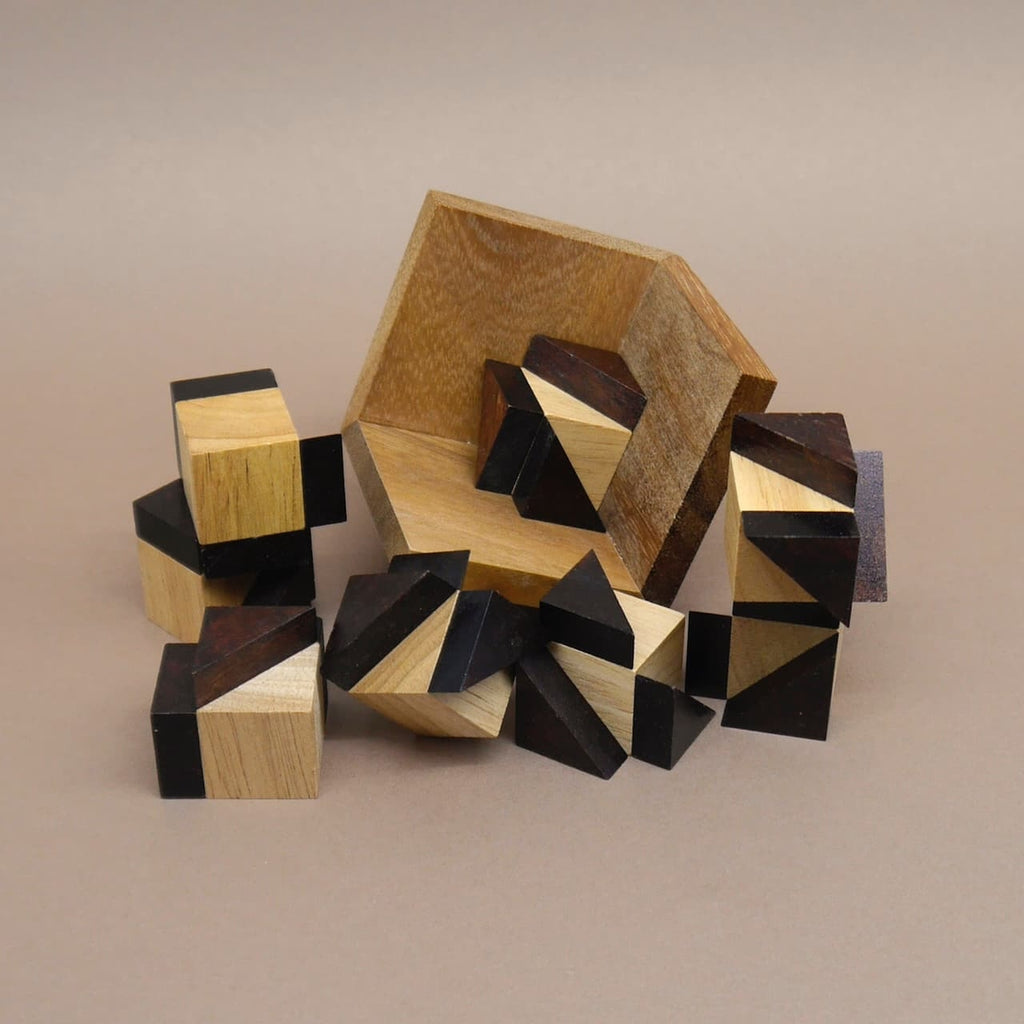 Verstreute holzspiel‑Elemente: segmentierte Miniwürfel aus hellem und dunklem Holz liegen vor einer gekippten Box