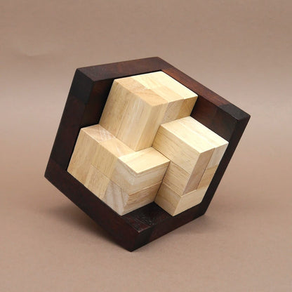 Komplett zusammengesetztes Geduldsspiel: hell‑dunkles 3D‑Holzpuzzle in kubischem Rahmen vor braunem Hintergrund.