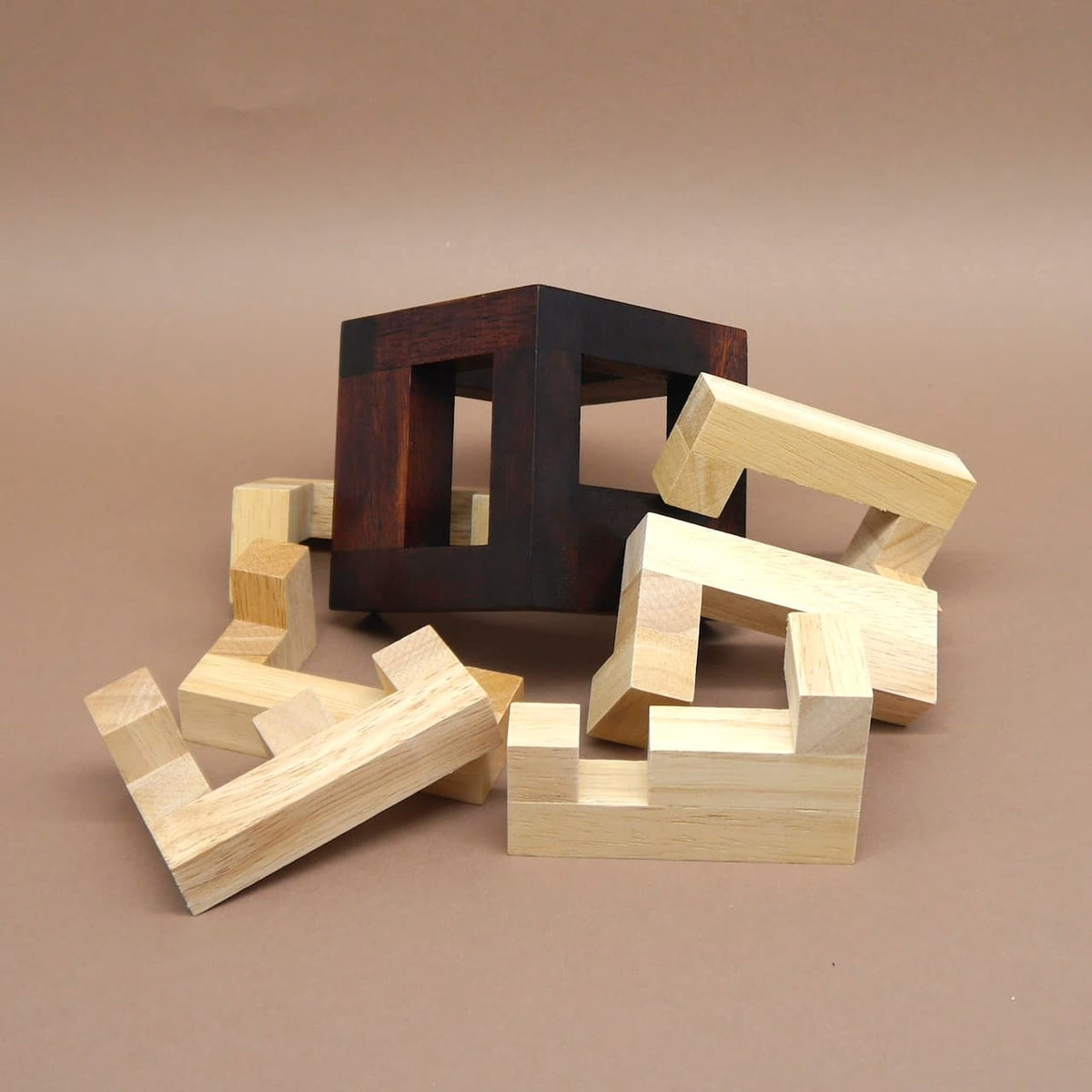 Zerlegte Holzbausteine und leerer Rahmen eines kniffligen Holzspiels – ideale Geschenkidee für Knobel‑Fans.
