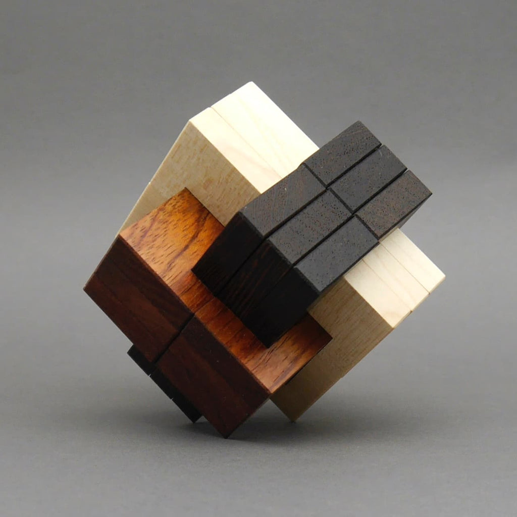 Holz-Knobelobjekt aus verschiedenfarbigen Bauteilen vor grauem Hintergrund, als dekoratives Denkspiel präsentiert.