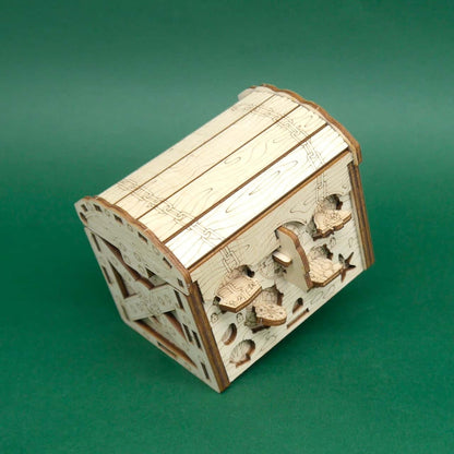 Geschlossene Schatztruhe-Puzzlebox aus hellem Holz mit eingravierten Ketten und Seesternen, schräge Seitenansicht vor grünem Hintergrund.