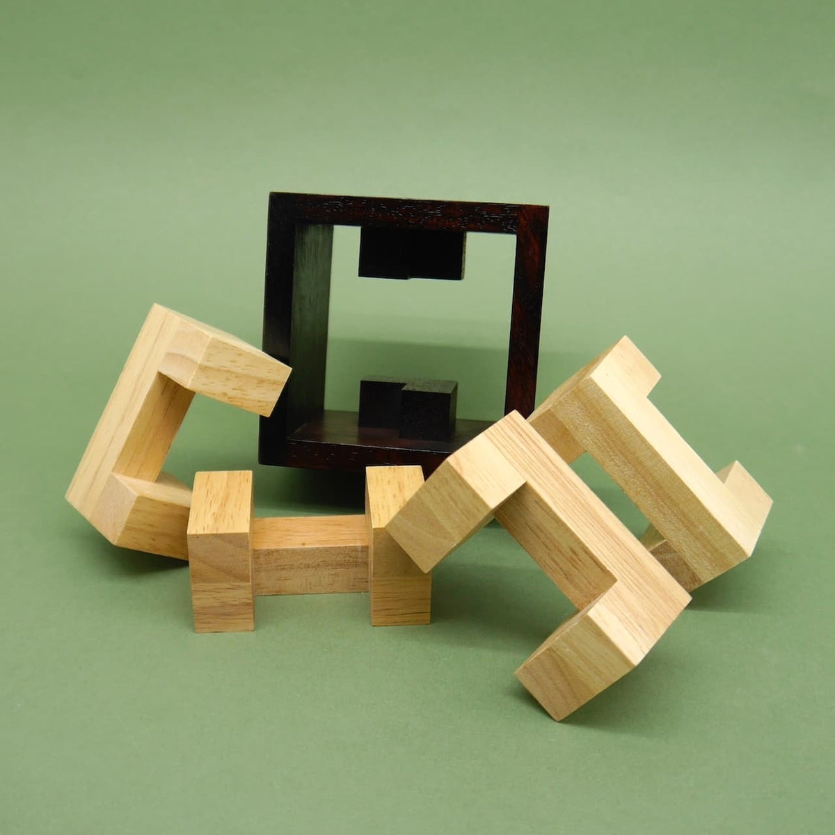Zerlegte Holzstücke liegen vor einem leeren Rahmen und warten darauf, als räumliches Logikpuzzle zusammengesetzt zu werden.