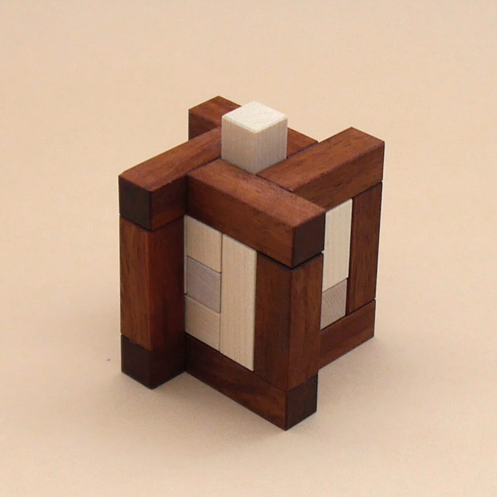 Holzwürfel mit sichtbaren Steckverbindungen und einem oberen Block, präsentiert als anspruchsvolles Knobelpuzzle aus Holz
