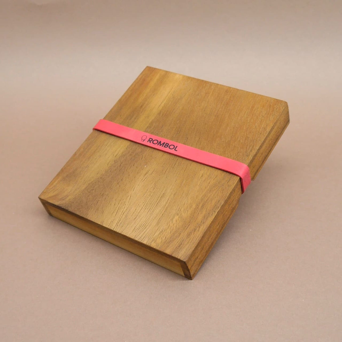Verschlossenes Holzpuzzle mit rotem Gummiband – ein kniffliges Denkspiel in edler Holzbox.