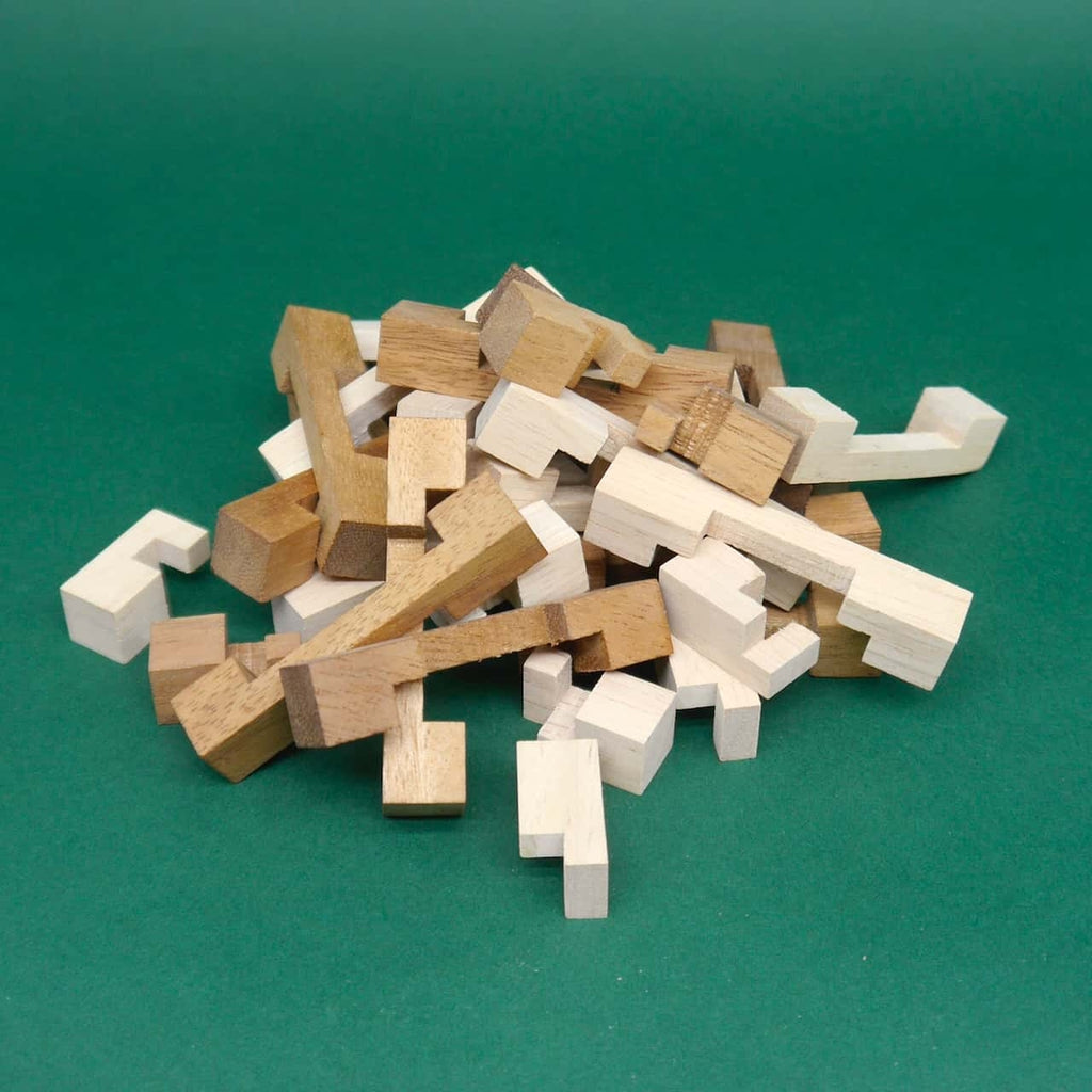 Haufen zerlegter L-förmiger und gerader Holzstäbe in hellen und dunklen Brauntönen auf grünem Untergrund.