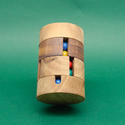 Aufrecht balancierendes Holz-Farbpuzzle mit vertikalen Spalten, die mehrere farbige Kugeln zeigen, vor monochrom grünem Hintergrund.