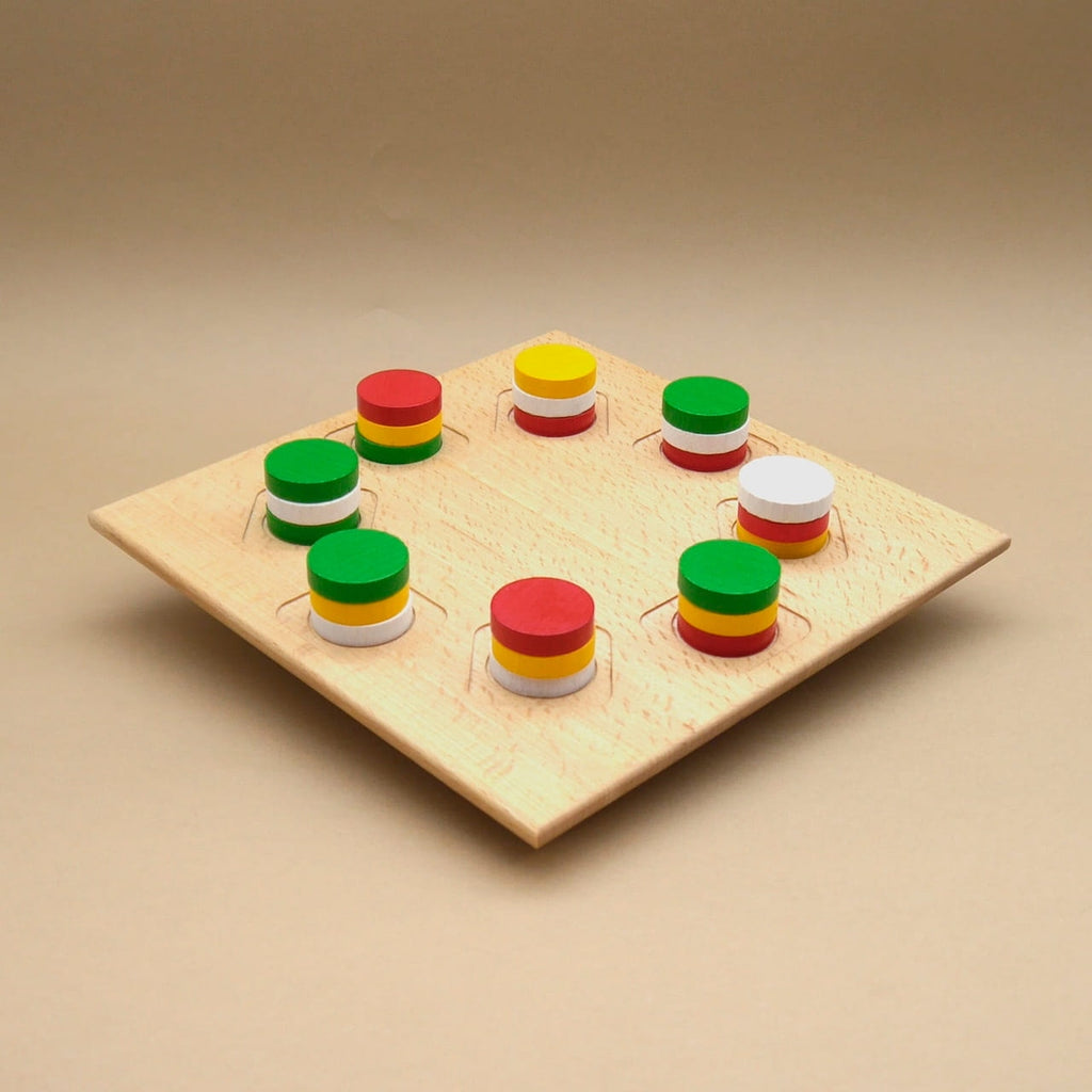 Rincala Strategiespiel: Holzbrett mit runden Vertiefungen, bunte gestapelte Scheiben im Kreis – taktisches Farbspiel für Familien.