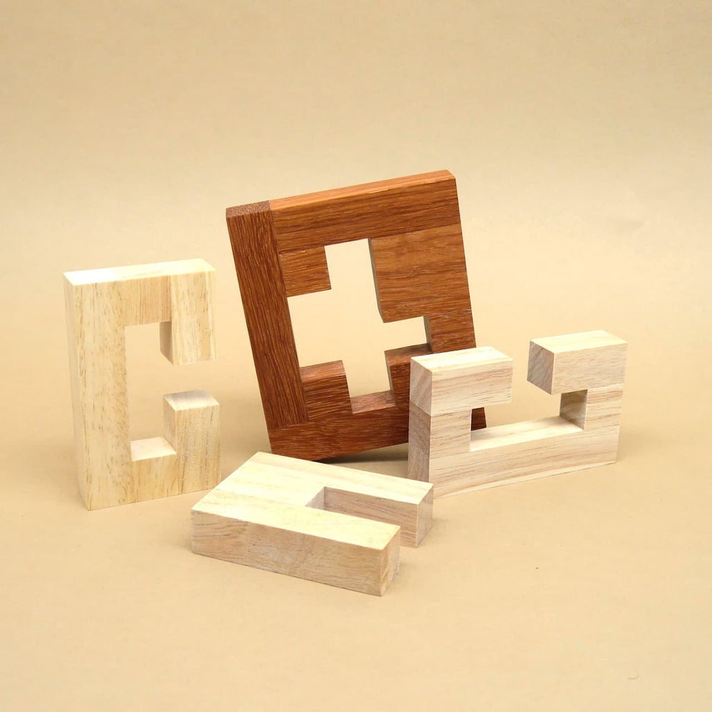 Mehrere lose Teile eines IQ-Puzzles aus hellem und dunklem Holz liegen ausgebreitet vor beigefarbenem Hintergrund