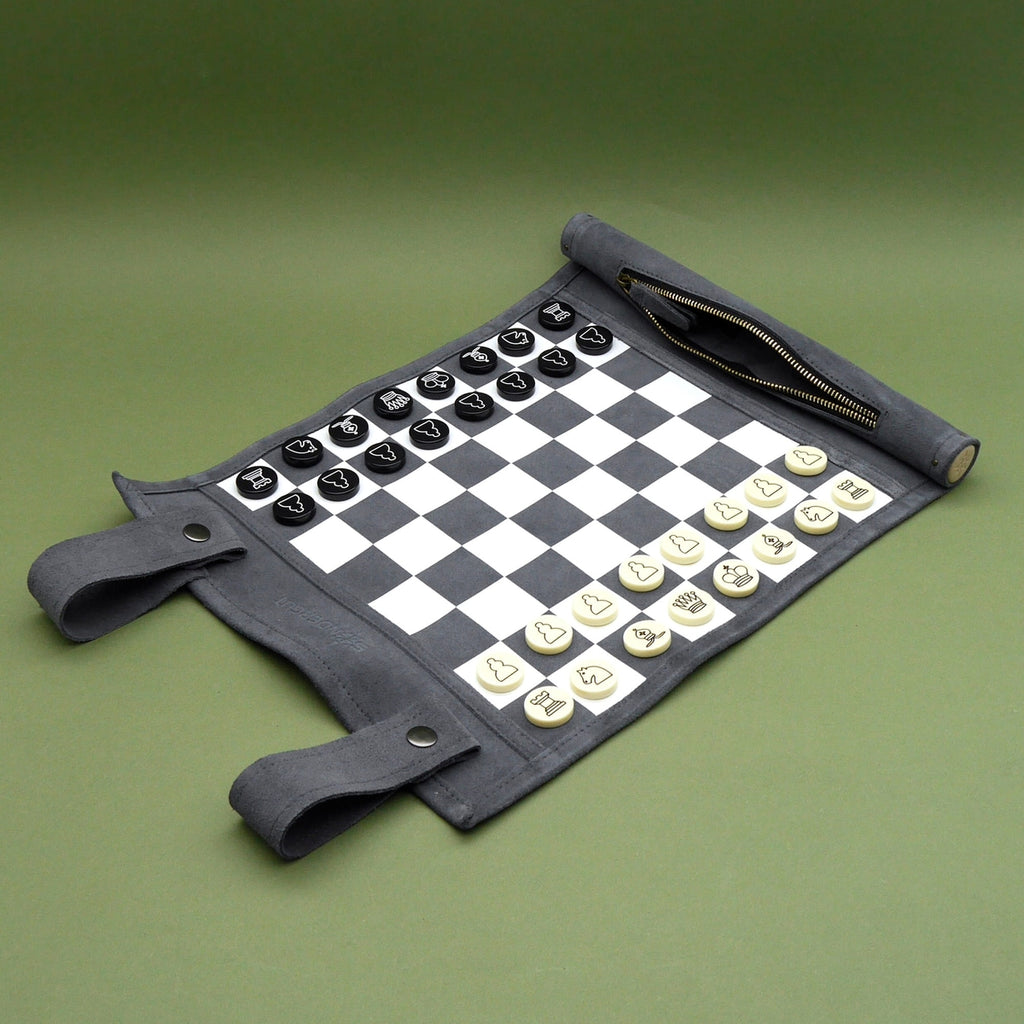 Rollbares Chess-Spiel mit schwarzen und weißen Figuren auf flexiblem Reisebrett aus grauem Material.