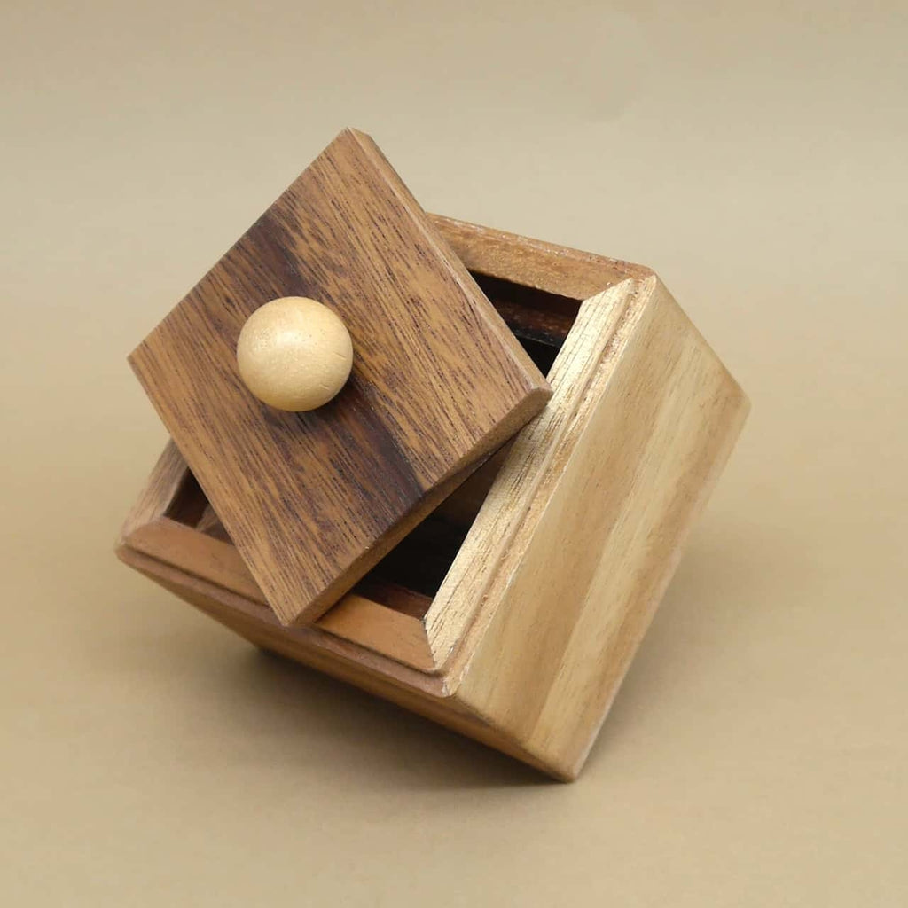 Teilgeöffnete Trickbox aus hellem Holz, Deckel mit Knauf schräg angelehnt, bereit zum Befüllen.
