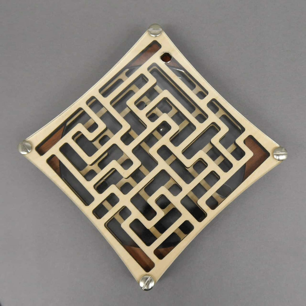 Draufsicht auf das Labyrinth-Puzzle, als Raute gedreht; verschachtelte Wege unter Plexiglas, winzige Metallkugel nahe der oberen Ecke.