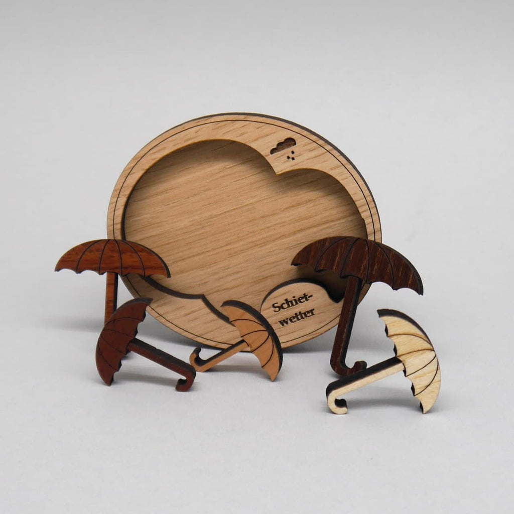 Holz-Legespiel „Schietwetter“ im Aufbau: Leere Wolken-Einlage mit fünf Regenschirm-Puzzleteilen, die locker davor angeordnet sind.