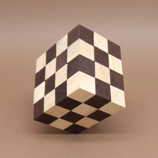 Perfekt zusammengesetztes Logikpuzzle: ein schwebend wirkender Würfel aus hellen und dunklen Holzquadern vor neutralem, braunem Fond.