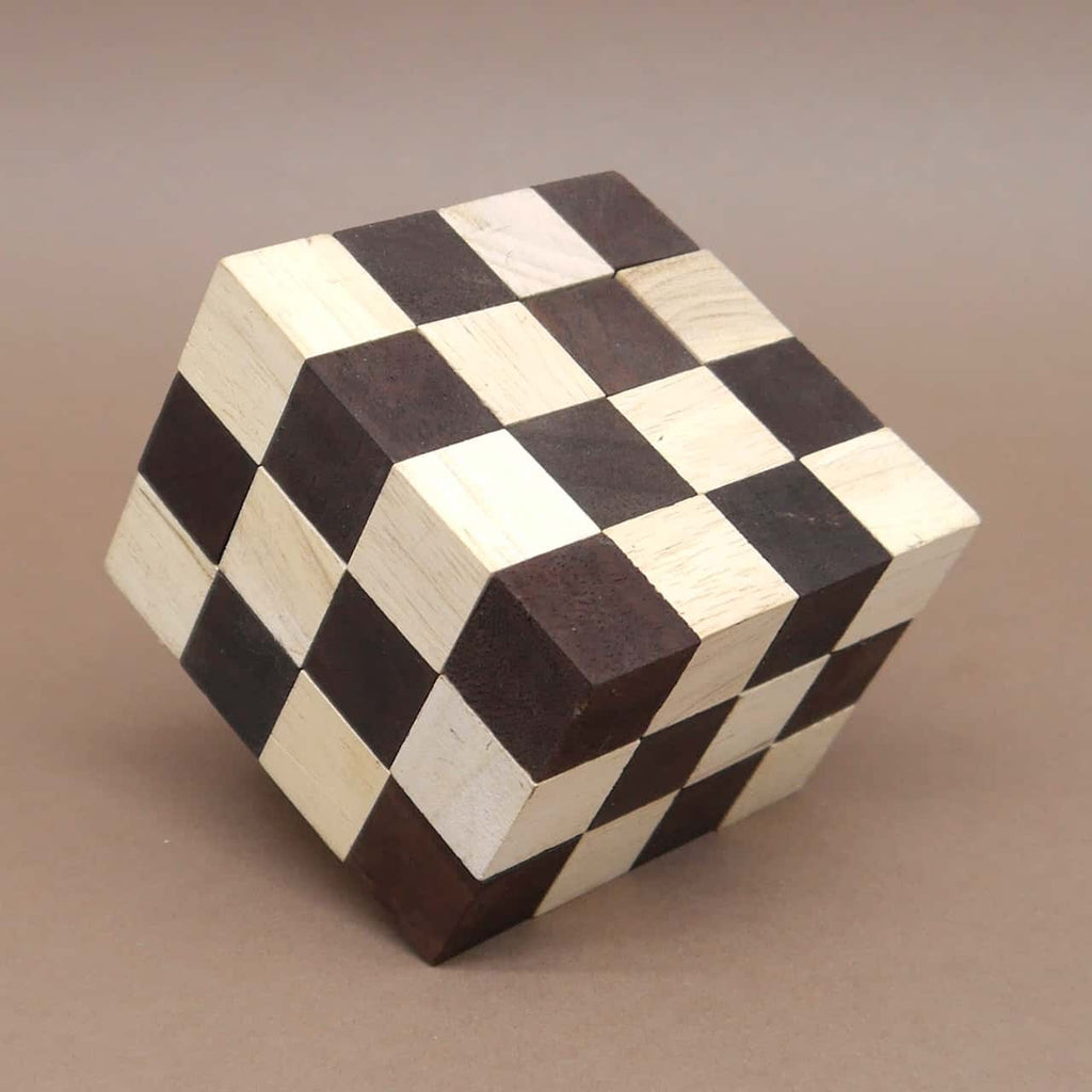 Gelöster Knobelspiel-Würfel mit schachbrettartigem Muster aus hellen und dunklen Holzwürfeln, leicht gekippt aufgestellt vor schlichtem Hintergrund.