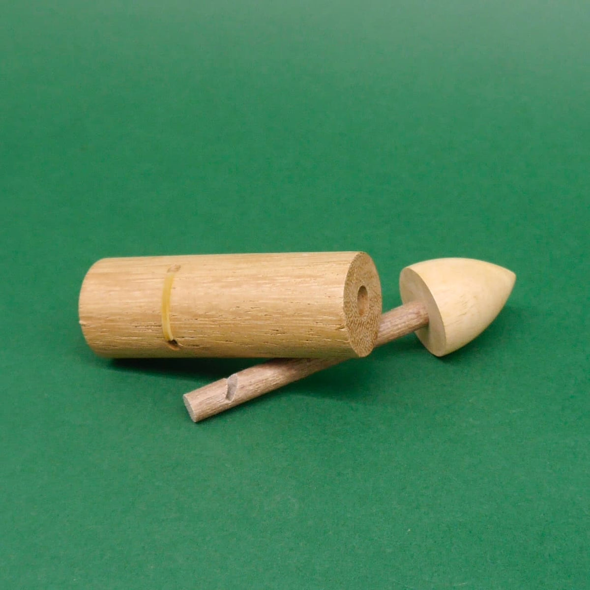 Holz‑Schnapper Trick‑Denkspiel: auseinandergebautes Geschicklichkeitsspiel / Braingame – zylindrischer Hohlkörper, Stab und konische Spitze liegen auf grünem Hintergrund.
