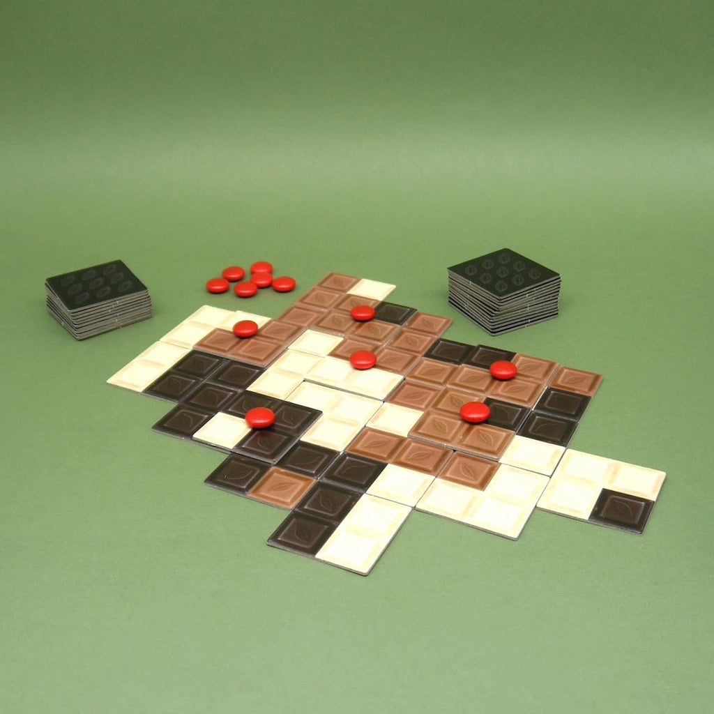 Ein ausgelegtes Spielfeld des Spiels 'Schokoly' mit roten Markern – ideal für einen unterhaltsamen Spieleabend mit Freunden oder Familie.