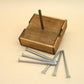 Holzbox mit mittigem Stab und sechs blanken Nägeln auf hellem Untergrund – minimalistisches Denkspiel zum Ausbalancieren.