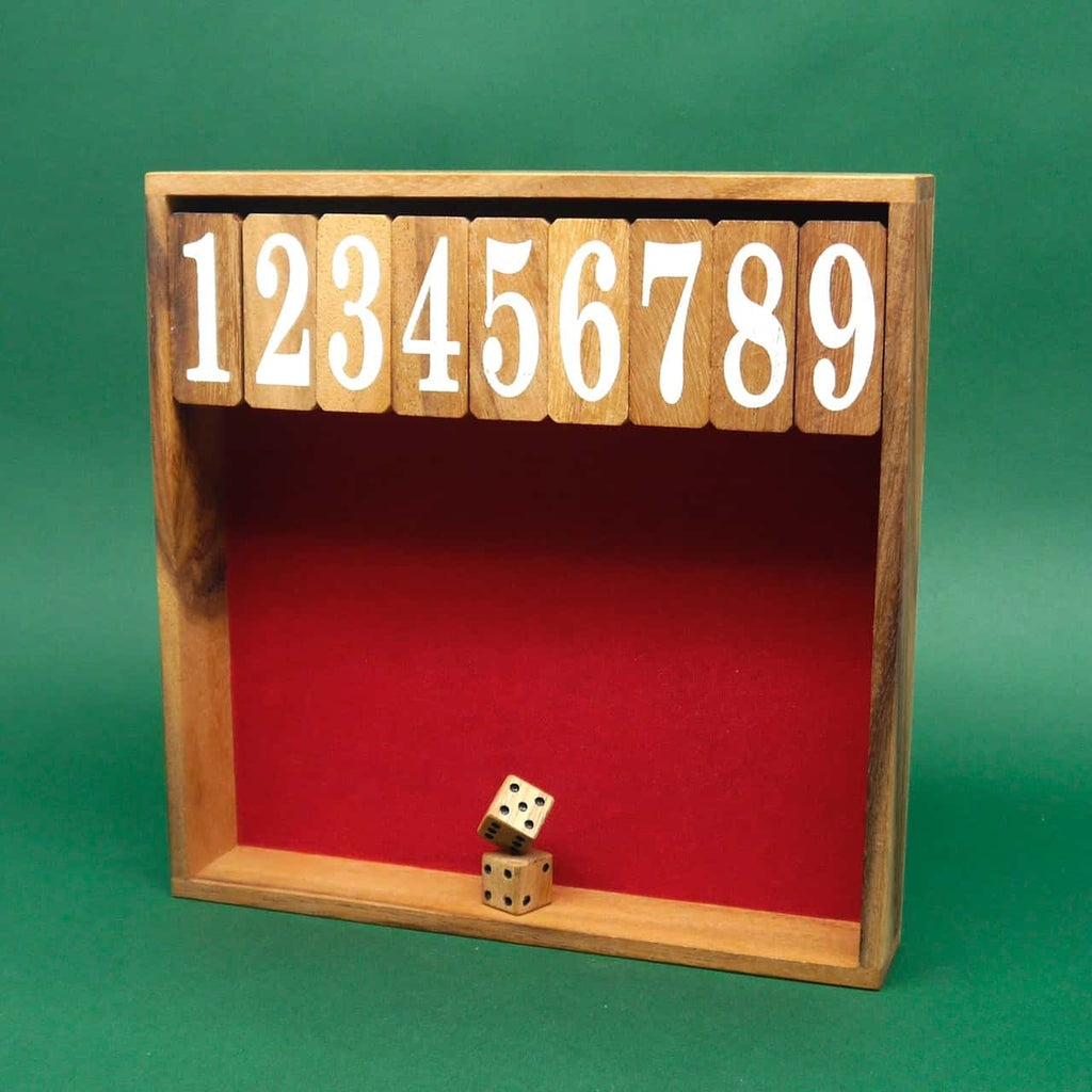 Ein klassisches Würfelspiel "Shut the Box" in einer Holzbox mit roter Spielfläche. Oben befinden sich nummerierte Klappdeckel von 1 bis 9, während unten zwei Holz-Würfel aufeinanderliegen. Der grüne Hintergrund hebt das Spiel hervor.