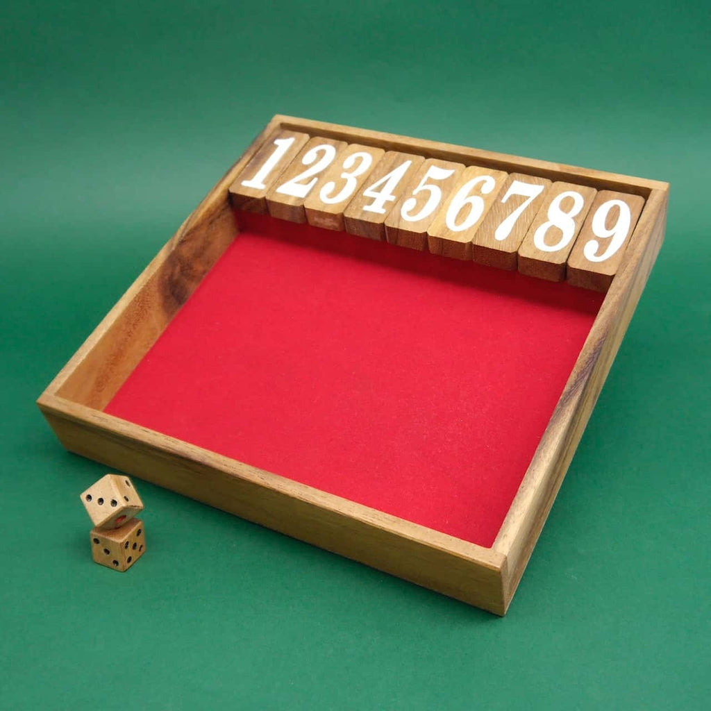Ein klassisches Würfelspiel "Shut the Box" aus Holz mit roter Spielfläche. Die Klappdeckel sind von 1 bis 9 nummeriert und oben angeordnet. Neben der Box liegen zwei Holz-Würfel auf einem grünen Hintergrund.