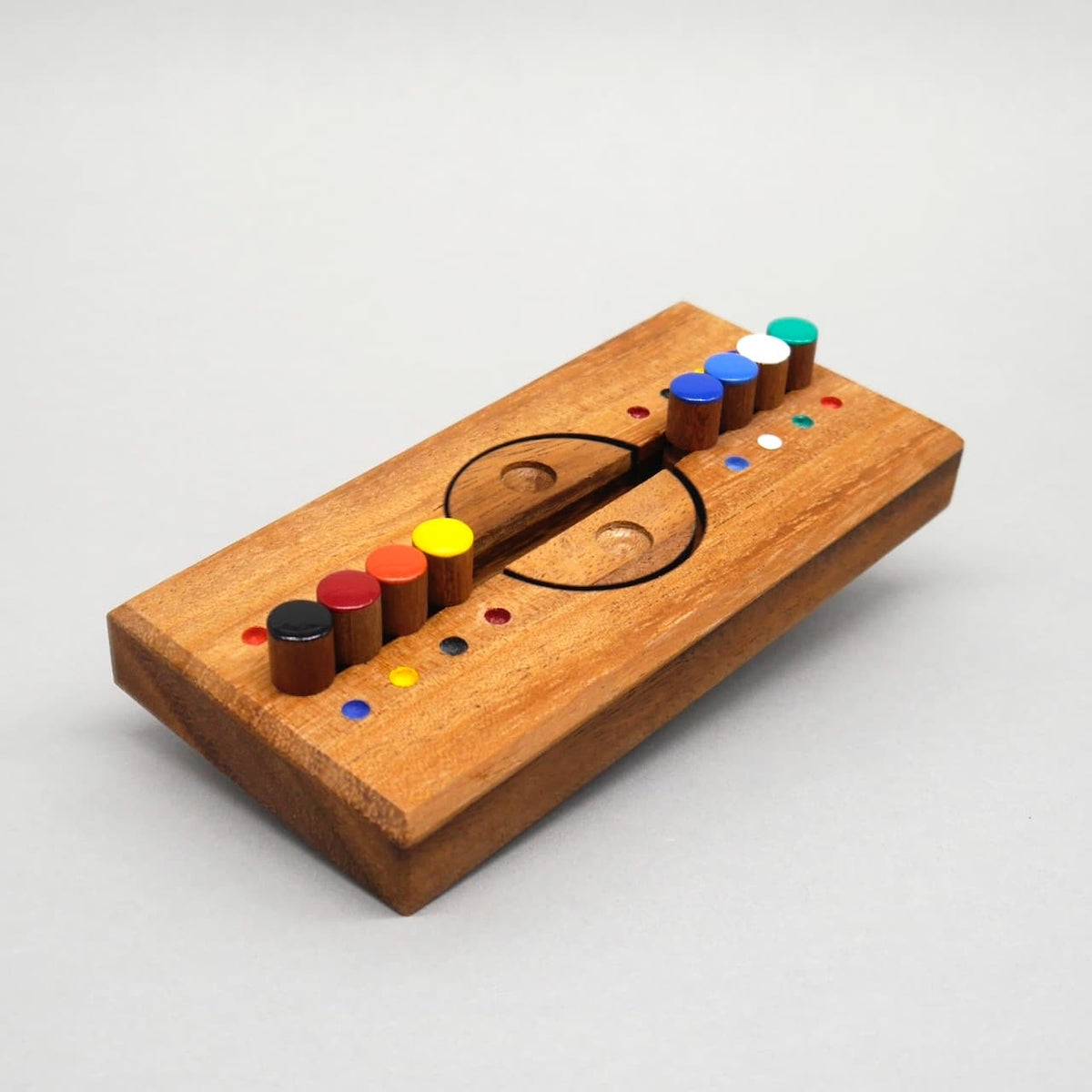 Längliches Holzpuzzle, bei dem links und rechts eines geteilten Kreises farbige Stifte sauber sortiert sind – ein cleveres Farbspiel zum Knobeln.