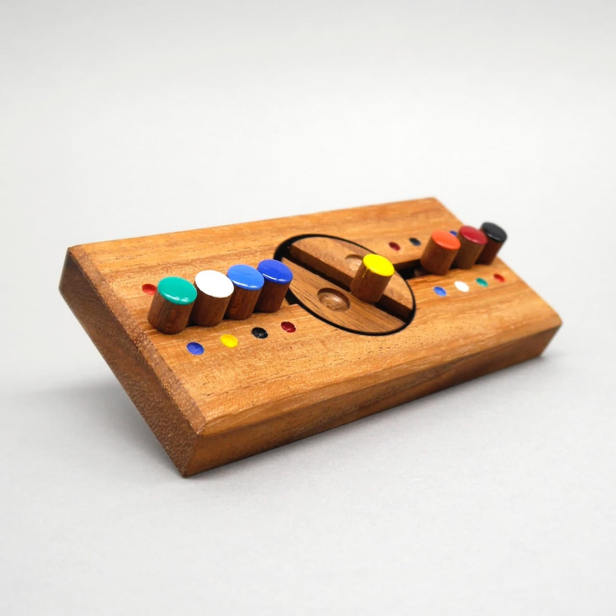 Schräg aufgestelltes Holz‑Geduldsspiel mit bunter Stiftreihe, die entlang einer Rille verschoben wird, um den richtigen Sicherheitscode zu finden.