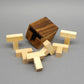 Geöffnete Holzbox neben allen sechs zerlegten, hellen T-Holzsteinen auf grauem Hintergrund – das „Six T“-Puzzle komplett auseinandergebaut.