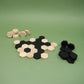 Aufgebaute Steine des lernspiel „SIX“: schwarze und helle Holzhexagone formen ein Muster, Reststapel liegen seitlich.