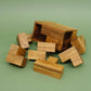 Einzelteile eines Holzpuzzles, verstreut vor der geöffneten Holzkiste – ein kniffliges Logikspiel.