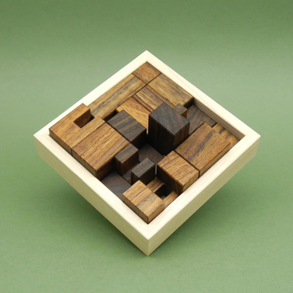 Packingpuzzle vollständig in einer quadratischen Holzbox verstaut, alle dunklen Holzteile dicht gepackt.