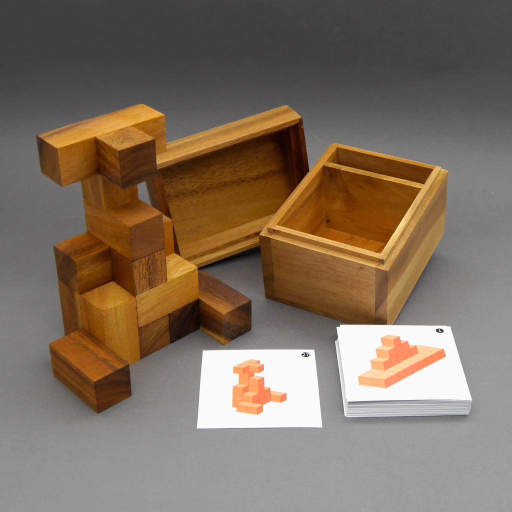 Soma Würfel Denkspiel: aufgebaute Holzfigur aus Klötzen neben offener Holzbox mit Fächern und Aufgabenkarten.