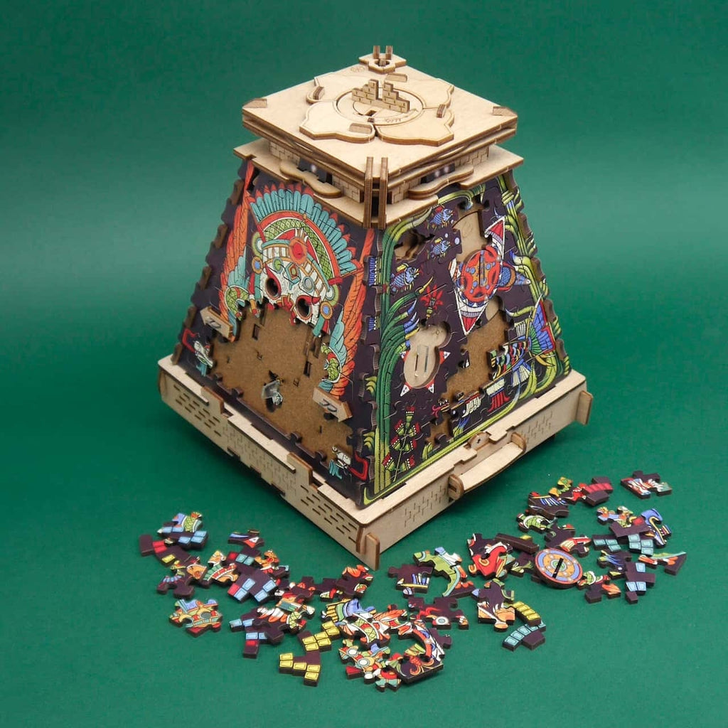 Aztekische Rätselbox/Puzzlebox mit reich verzierten Seiten, offenen Steckplätzen und verstreuten Puzzleteilen auf dem Tisch