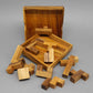Einzelne Holzpuzzle-Teile des „Spiel des Lebens“ verstreut vor der Holzbox – ein anspruchsvolles Holzpuzzle.