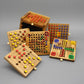 Sechs herausgenommene Spielbretter mit bunten Stiften zeigen ein vielseitiges Strategiespiele-Set aus Holz.