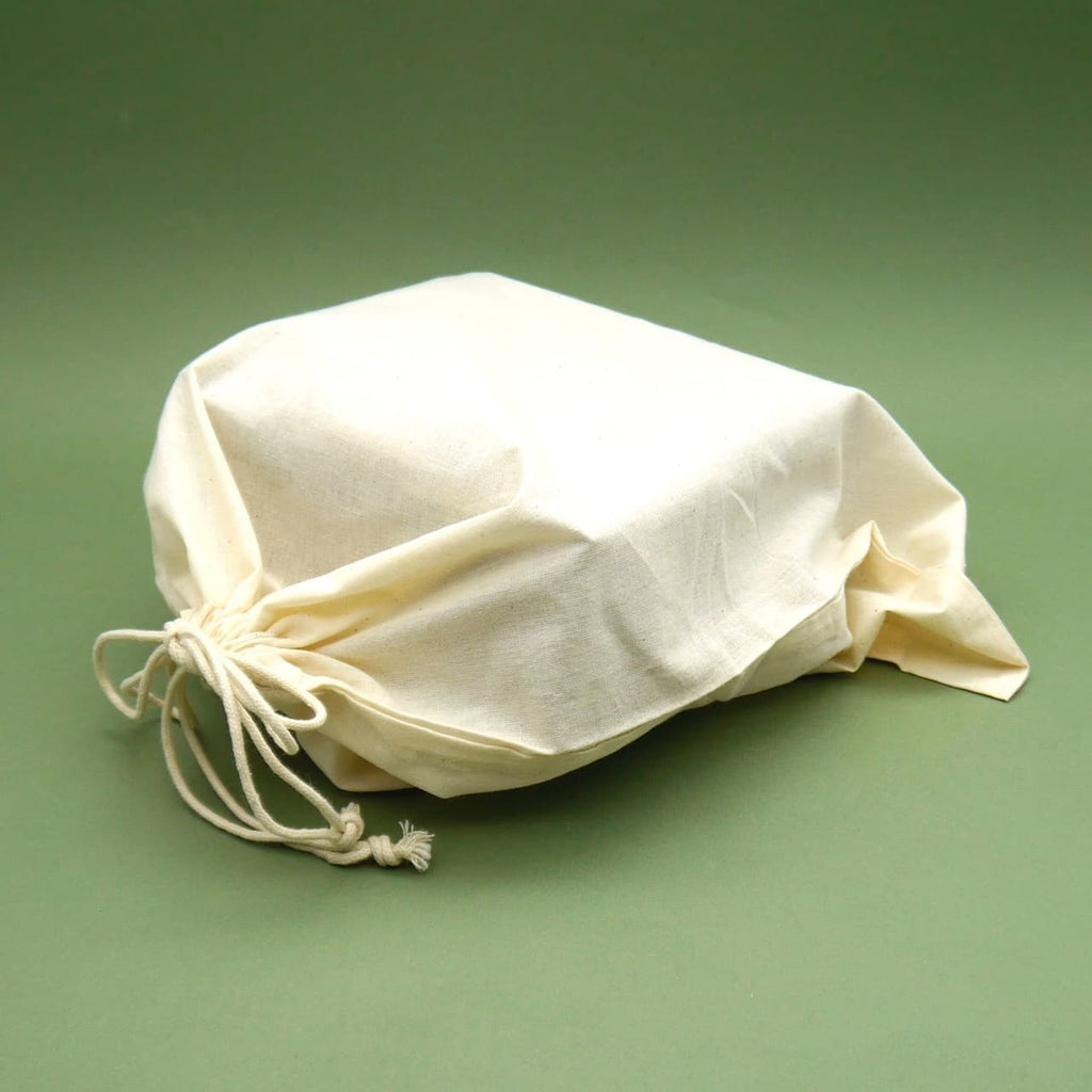 Brettspiel-Beutel aus naturfarbenem Stoff mit Zugband auf grünem Hintergrund.