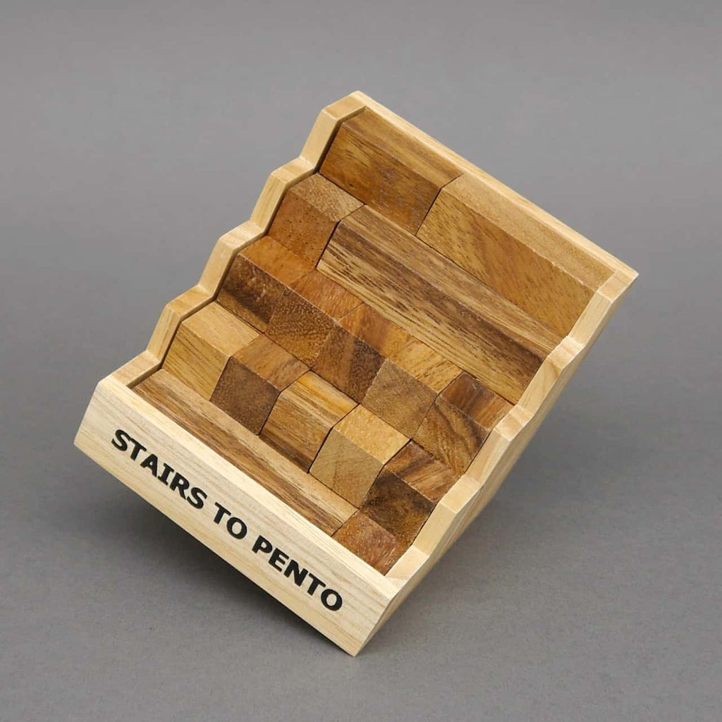 Schräg gestellte Box des Geduldsspiel „Stairs to Pento“, komplett gefüllt mit passgenau ineinander­gesetzten Holzklötzen.