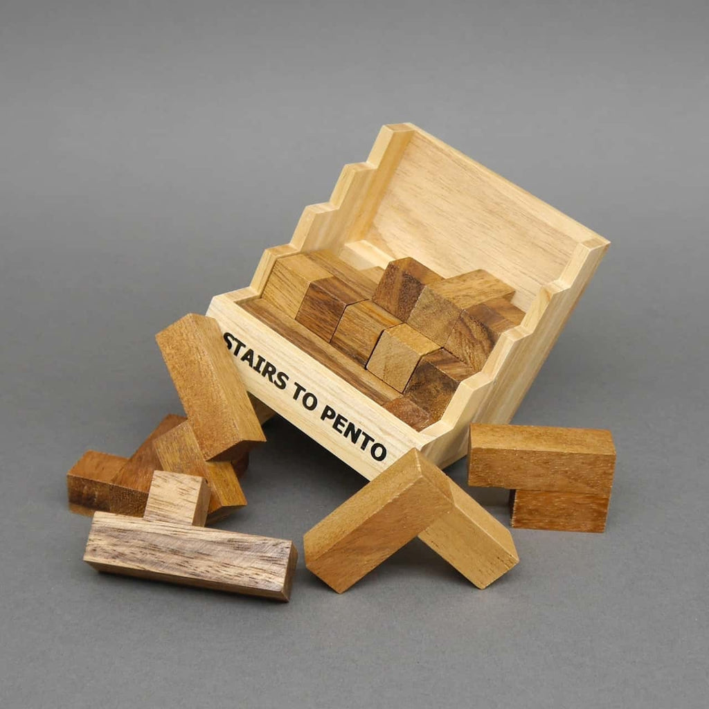 Kippende Box des 3dpuzzle „Stairs to Pento“; mehrere rechteckige Pentominos rutschen heraus und liegen davor auf dem Tisch.