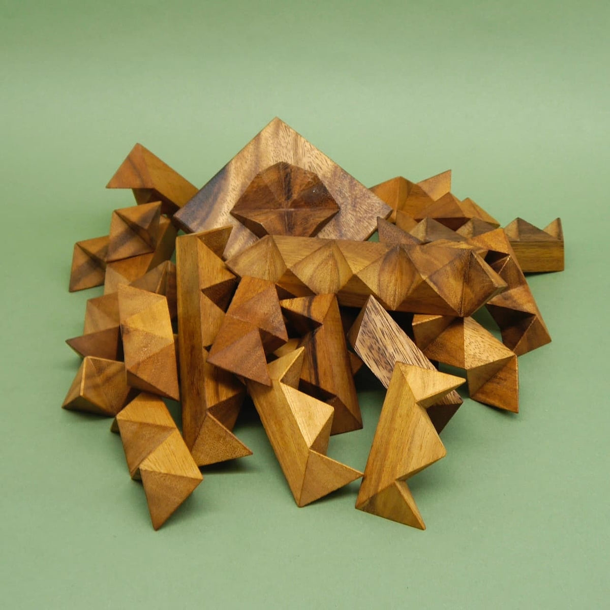 Holzpuzzle: Viele dreieckige Holzsegmente liegen verstreut vor einer flachen Grundplatte – ein unmontierter Sternpuzzle‑Bausatz.